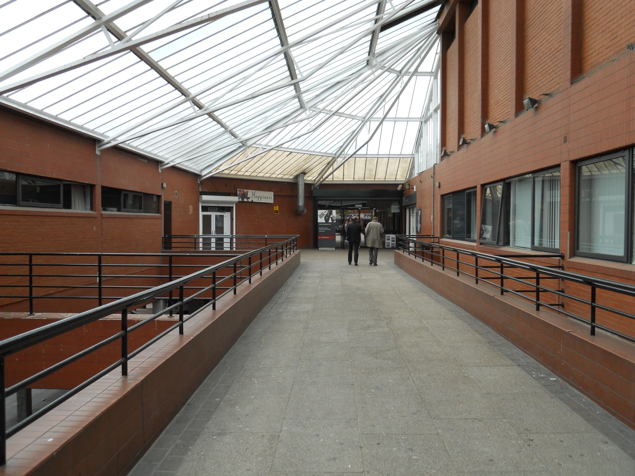 two people are walking inside the walkway between buildings