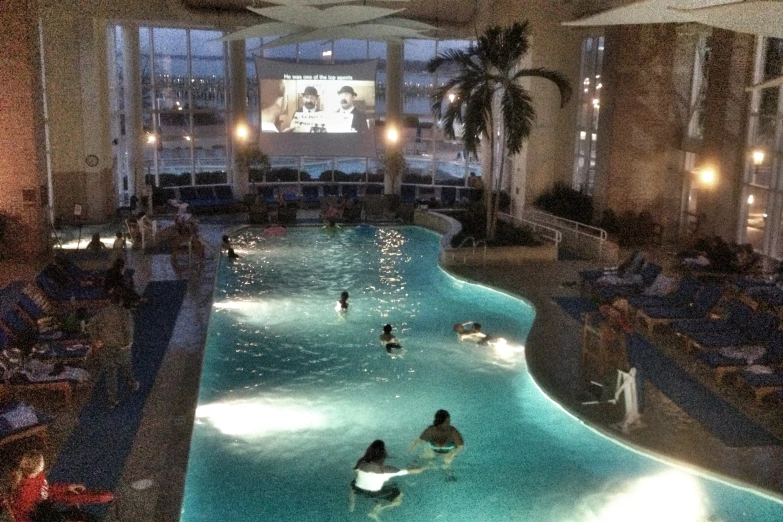 a swimming pool inside of a building surrounded by furniture