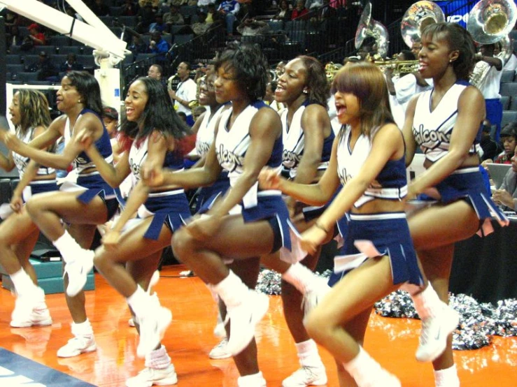 a group of cheerleaders on the basketball court with one sitting in the row