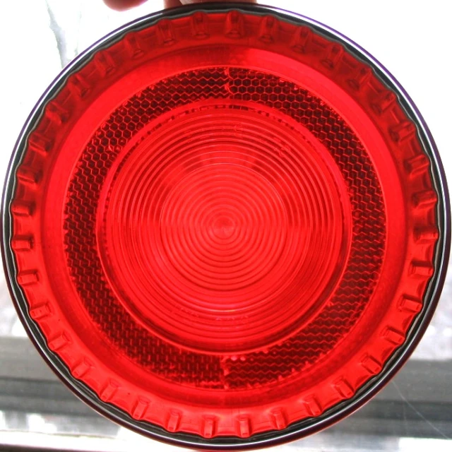 red stop light with someone holding it on top of a window