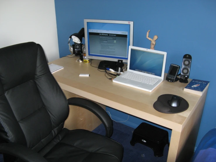 there is a chair in front of a desk with two computers on it