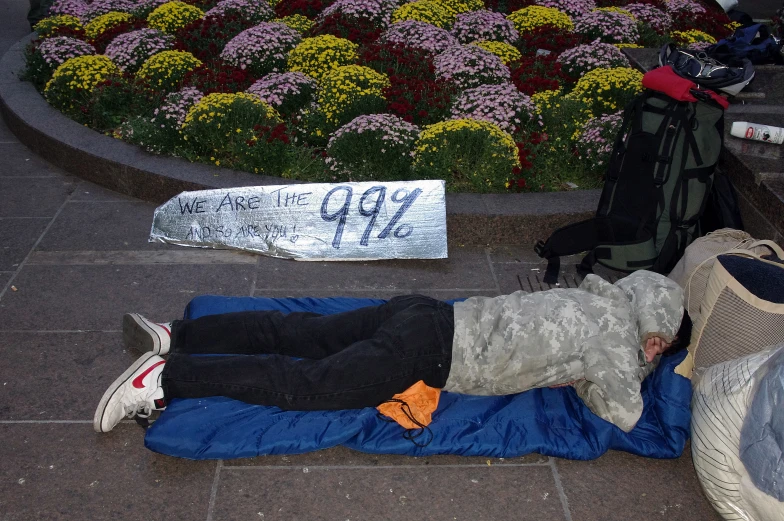 there is a man lying on the street with a snowboard