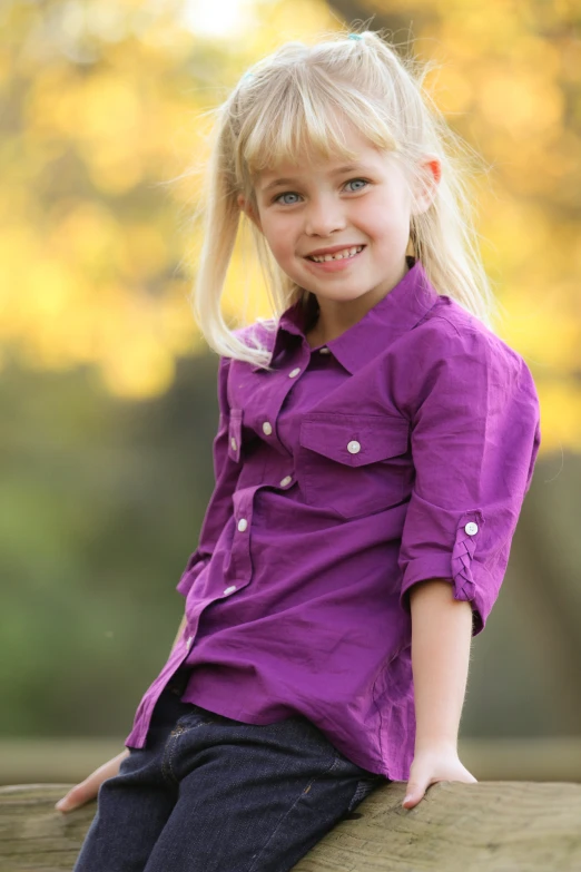 a young blonde girl smiling while posing for a picture