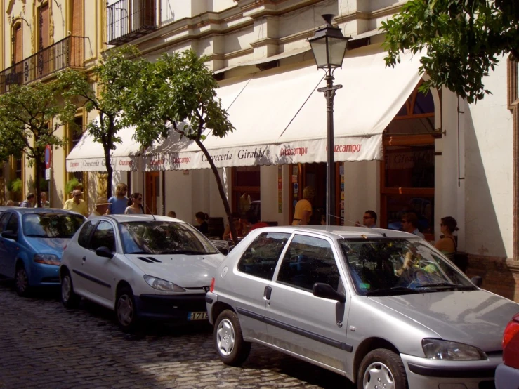 a silver car is parked near another car on the side of the street