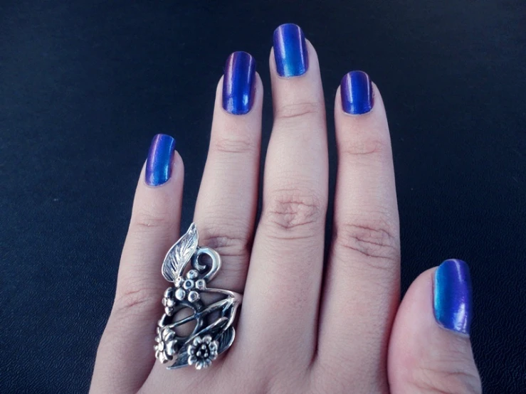 a woman with a purple manicure and a flower ring