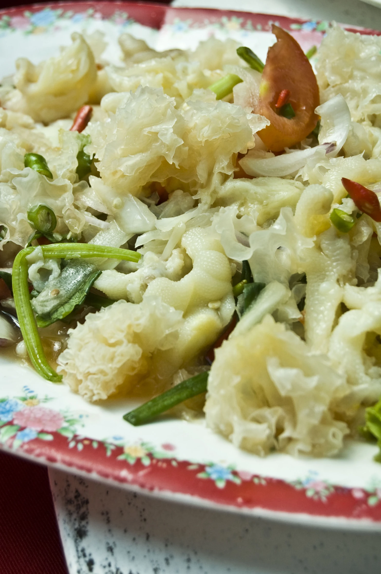 an asian food dish sits on a red and white plate