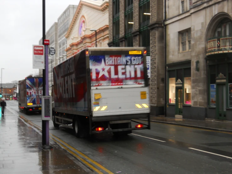 a big truck is driving down a rain soaked street