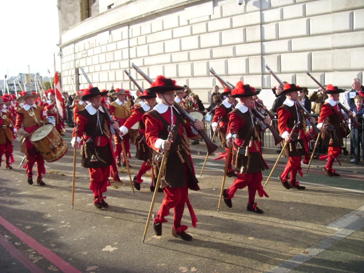 men in uniform and red hats are marching down the street