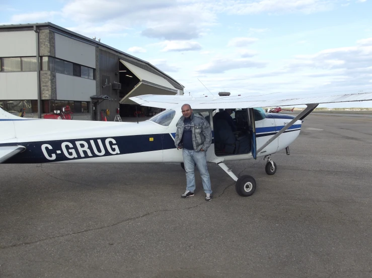 man standing outside of small blue and white plane