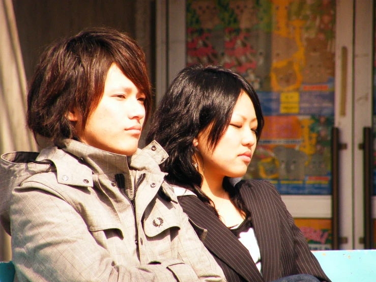 a pair of people sitting next to each other on a bench