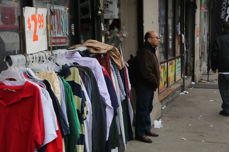 a man stands in front of a clothing store selling clothes