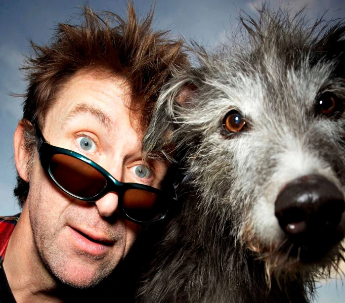 a man wearing sunglasses has a dog and has his nose to the camera