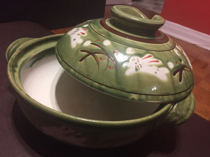 an ornate, green ceramic bowl with lid and flower designs on it