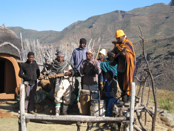 several men in costumes on a farm near huts