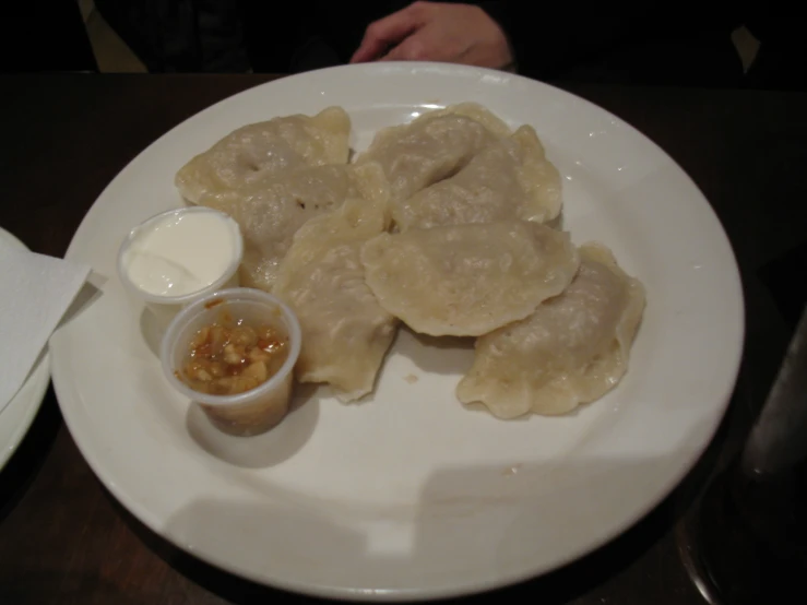 dumplings on a white plate with a side of sauces