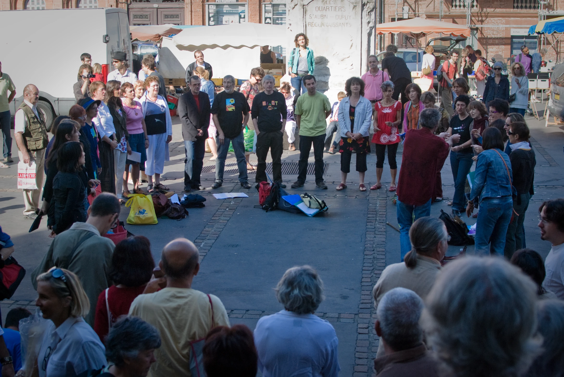 a man in a yellow jacket speaks to an audience on the street