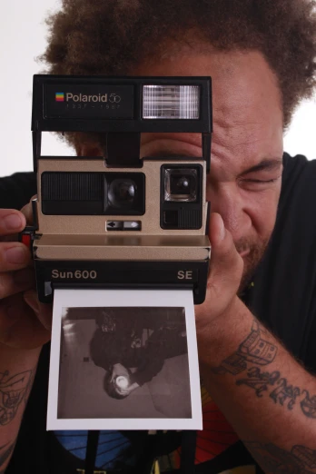 a man with his face behind a polaroid camera