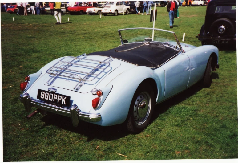 an older style sports car is displayed in a field