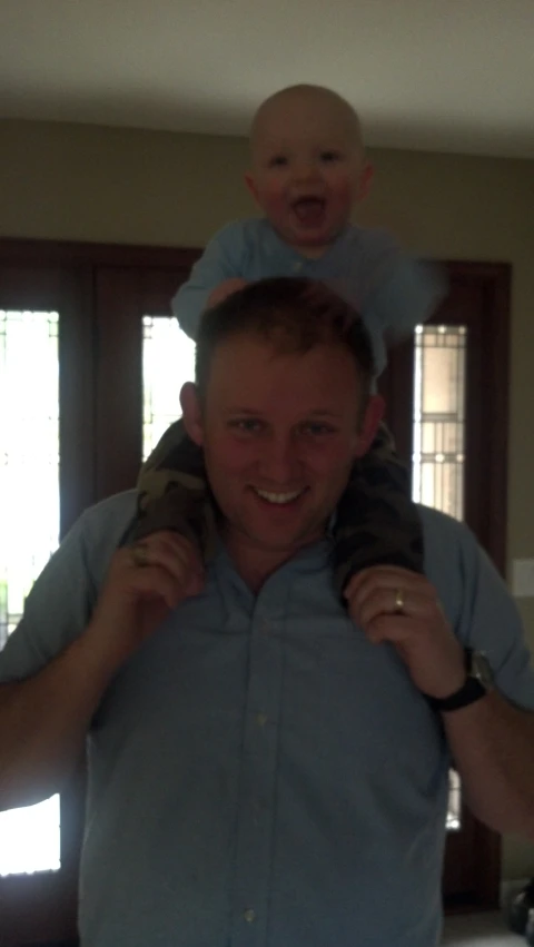 a man carrying his baby in his arms and smiling