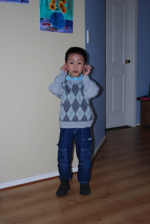 a boy holding up his hands near his ears