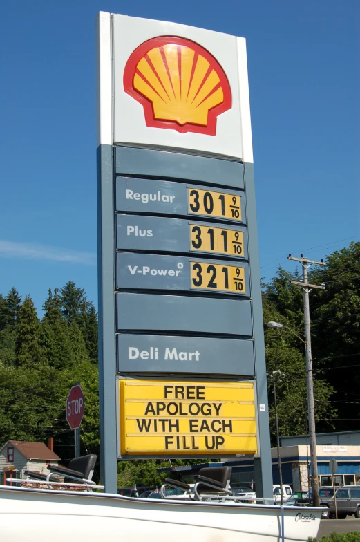 a large gas station sign in front of some trees