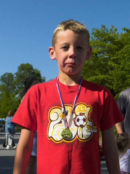 a boy wearing a red shirt and a medal