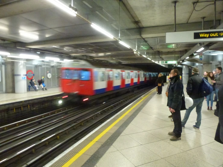 some people walking next to a train at a subway station