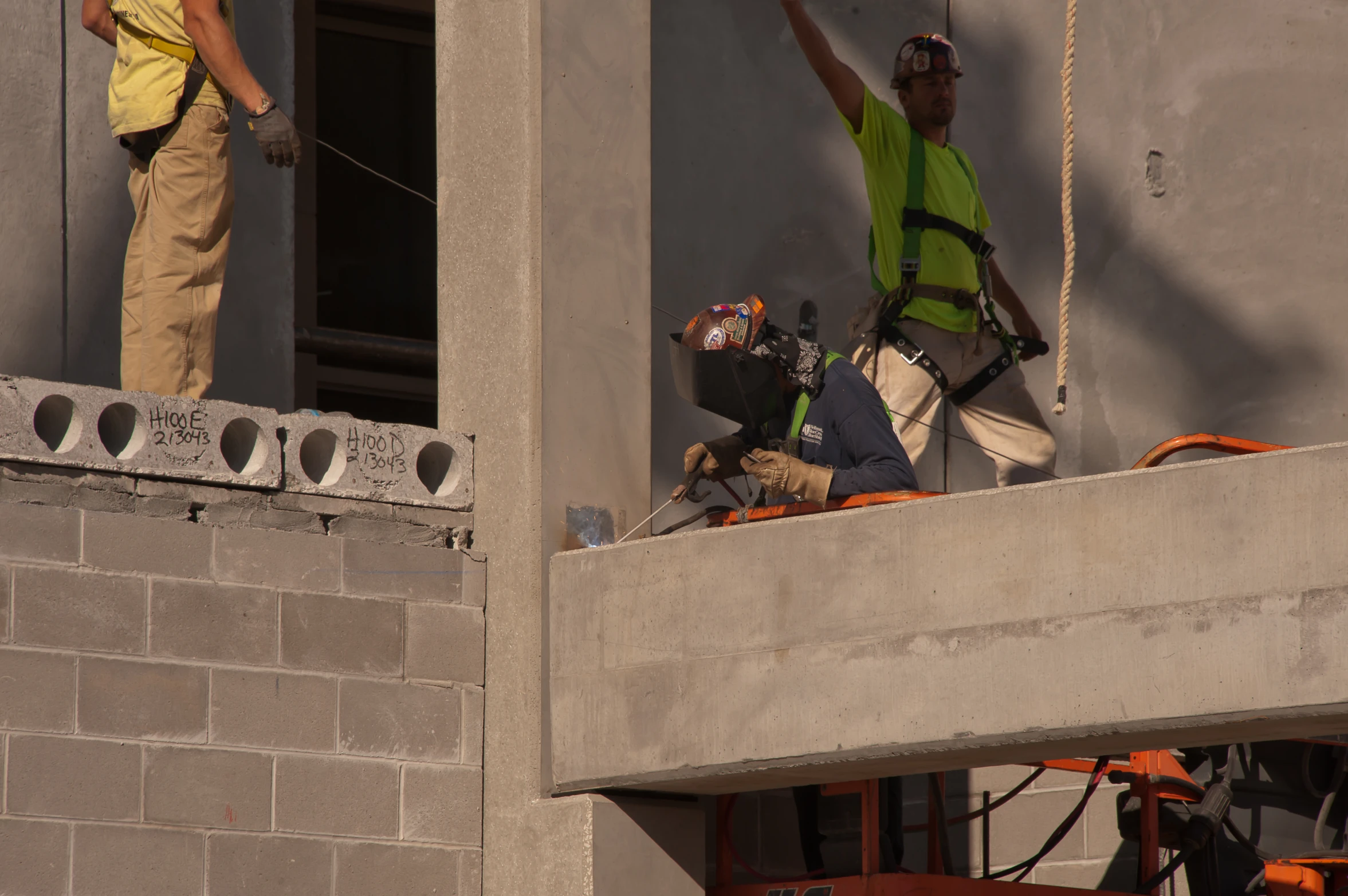 two men standing outside of a window with construction equipment on the ledge