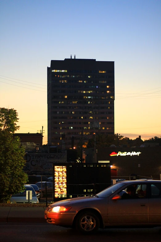 some cars driving on the road in front of buildings at night