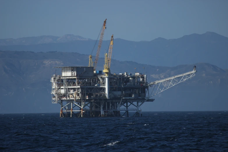 an oil rig on a large body of water near mountains