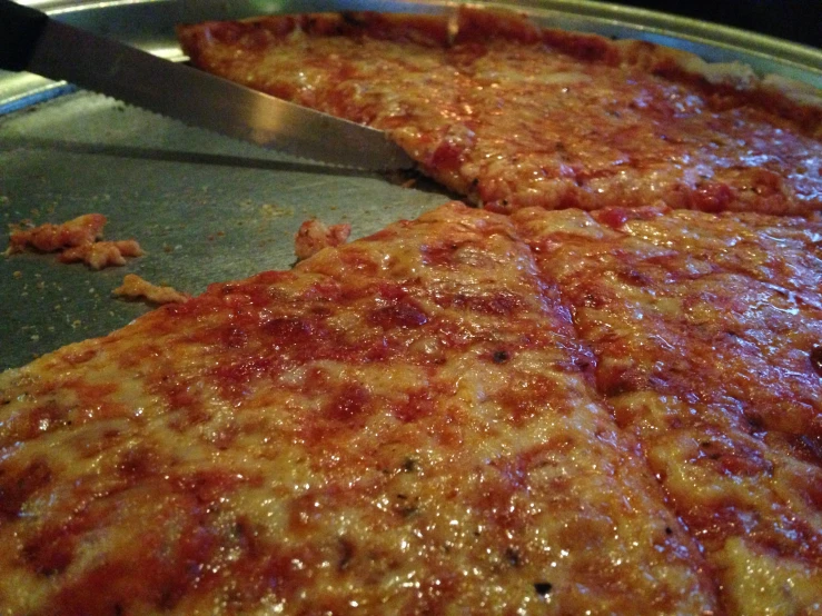 half eaten cheese pizza being cut with a knife