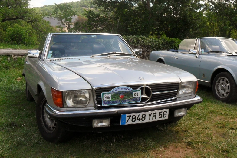 two older cars parked on grass beside each other