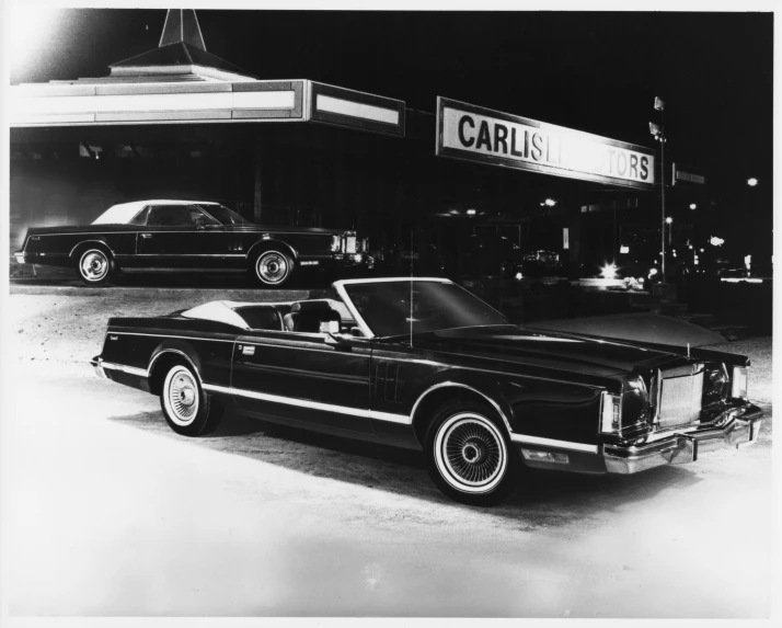 a black and white po of a car parked by a gas station