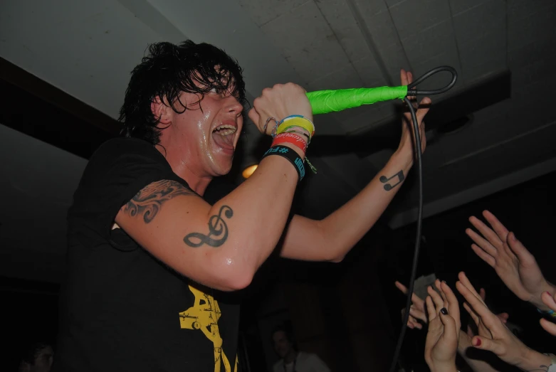 a man with tattoos and green hair singing into a microphone