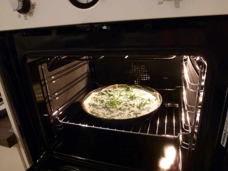 a pizza cooking in an open oven on the stove