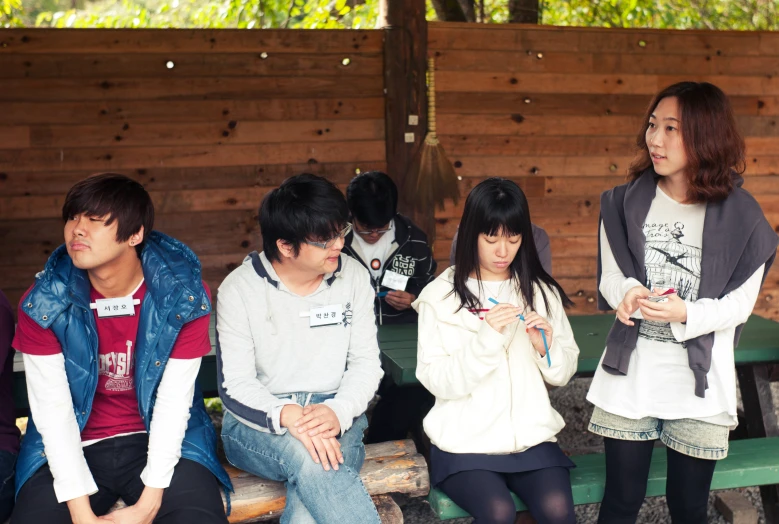 four people are sitting on a green bench