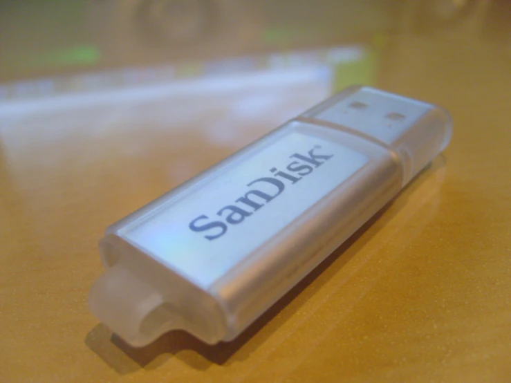 a silver sandisk flash drive sits on a wood table