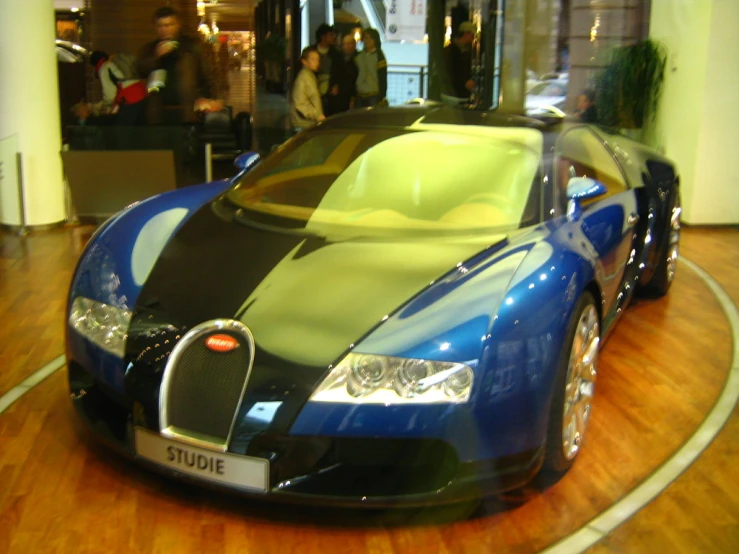 a blue car parked in the middle of a large wooden floor