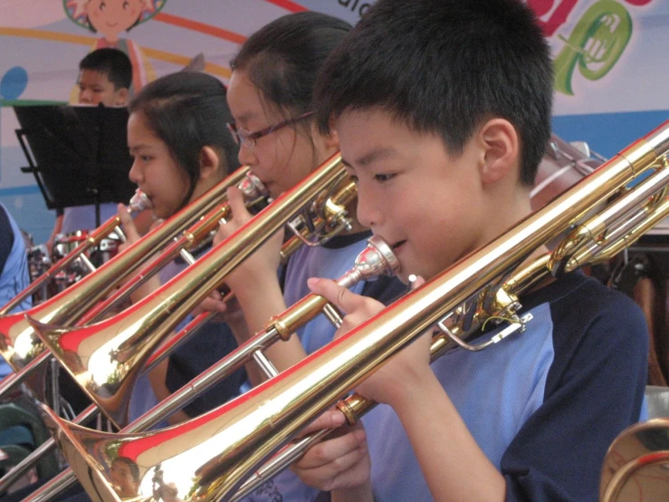 children playing instruments in a music class with a man playing the trumpet