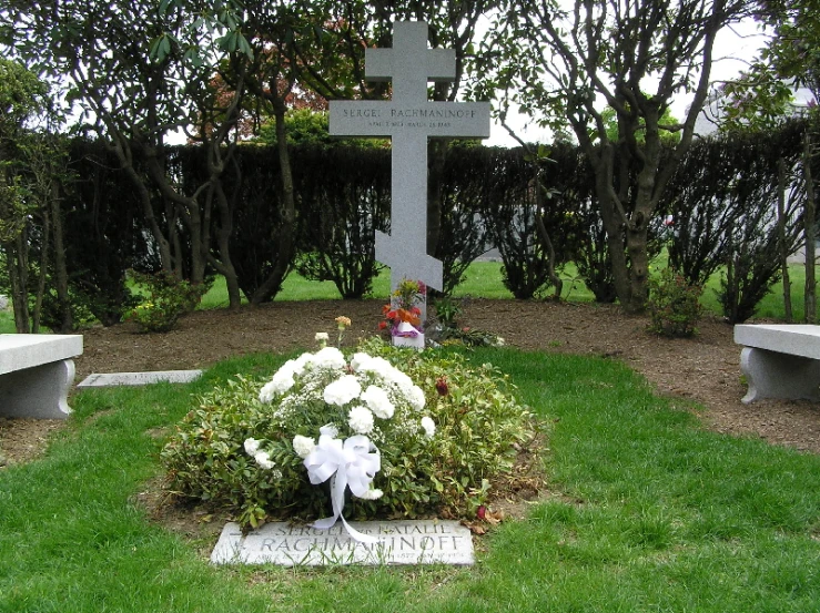 a flower bed is near a gravestone with flowers in it