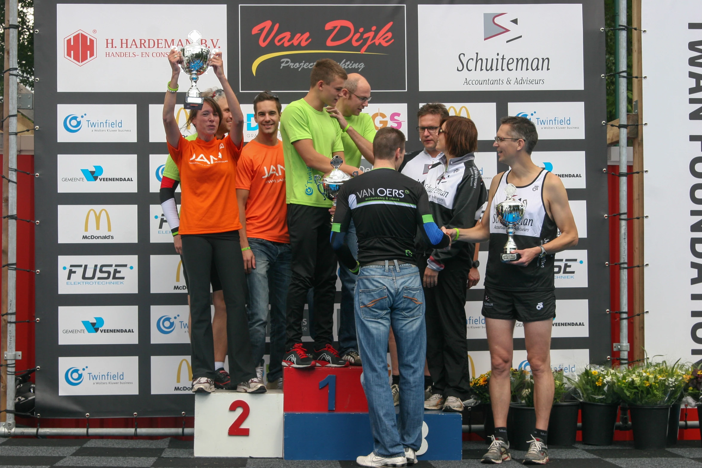 four people on a podium with one holding a trophy