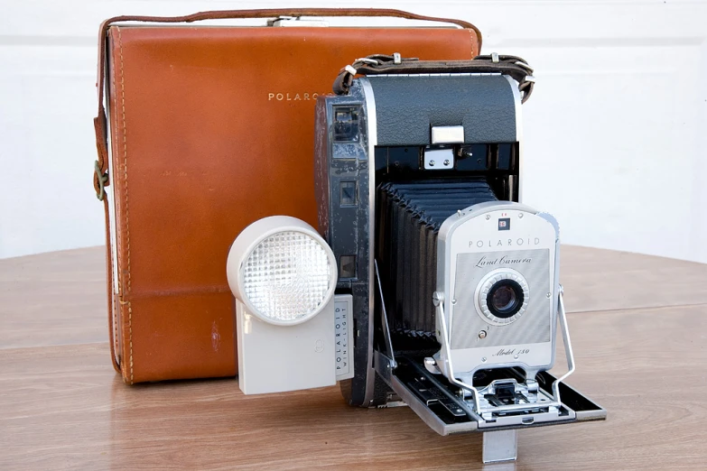 an old fashioned camera on a table next to a piece of luggage