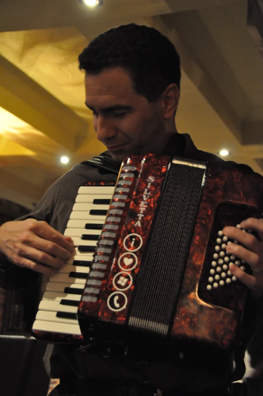 the man is holding a red and black accordion