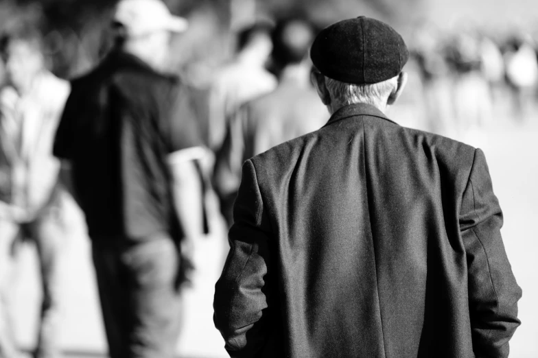 a man in a cap and coat walking past another man