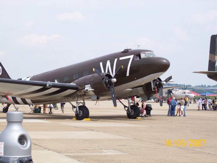 a propeller airplane parked in an airport with many people