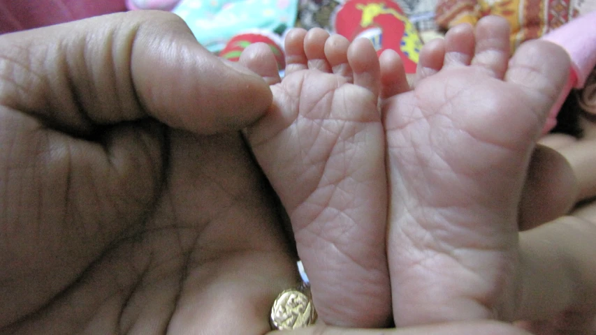 a baby with big legs held in human hands