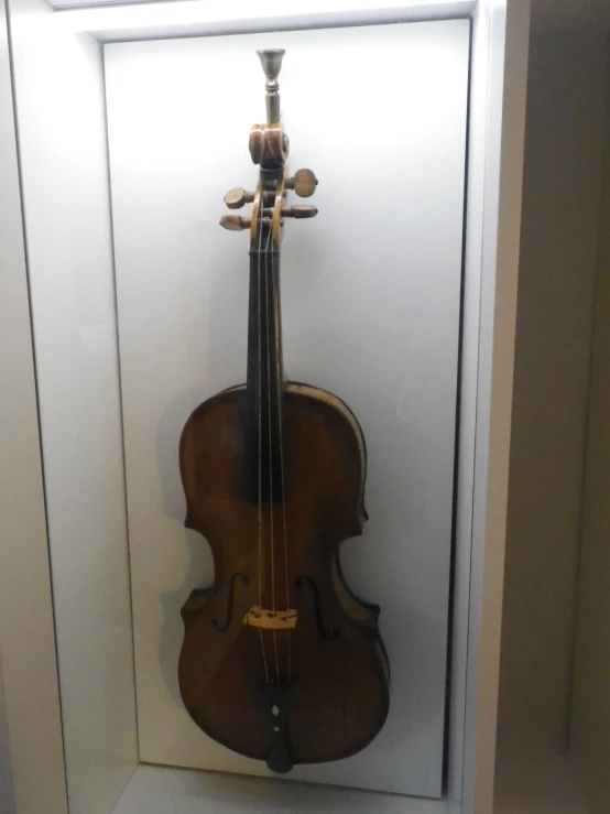 a violin is displayed in a case on a white wall