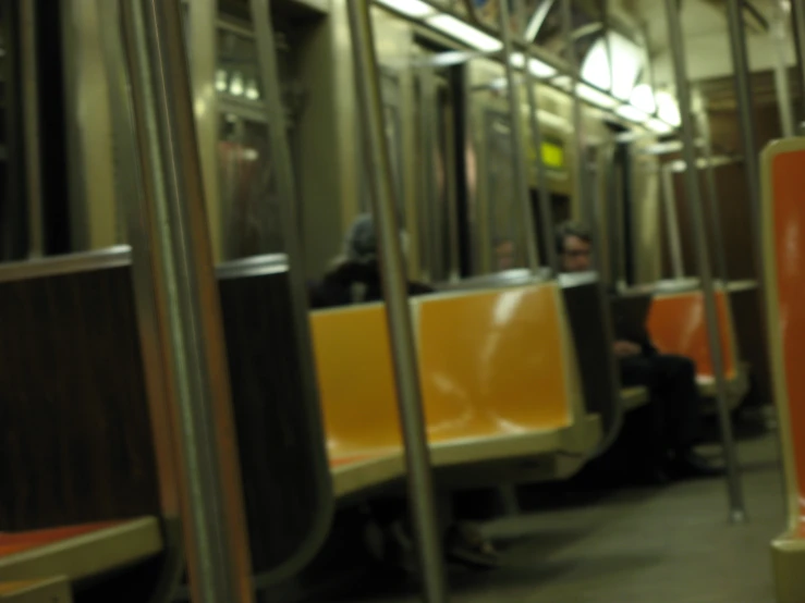 two people sitting on a subway car next to poles