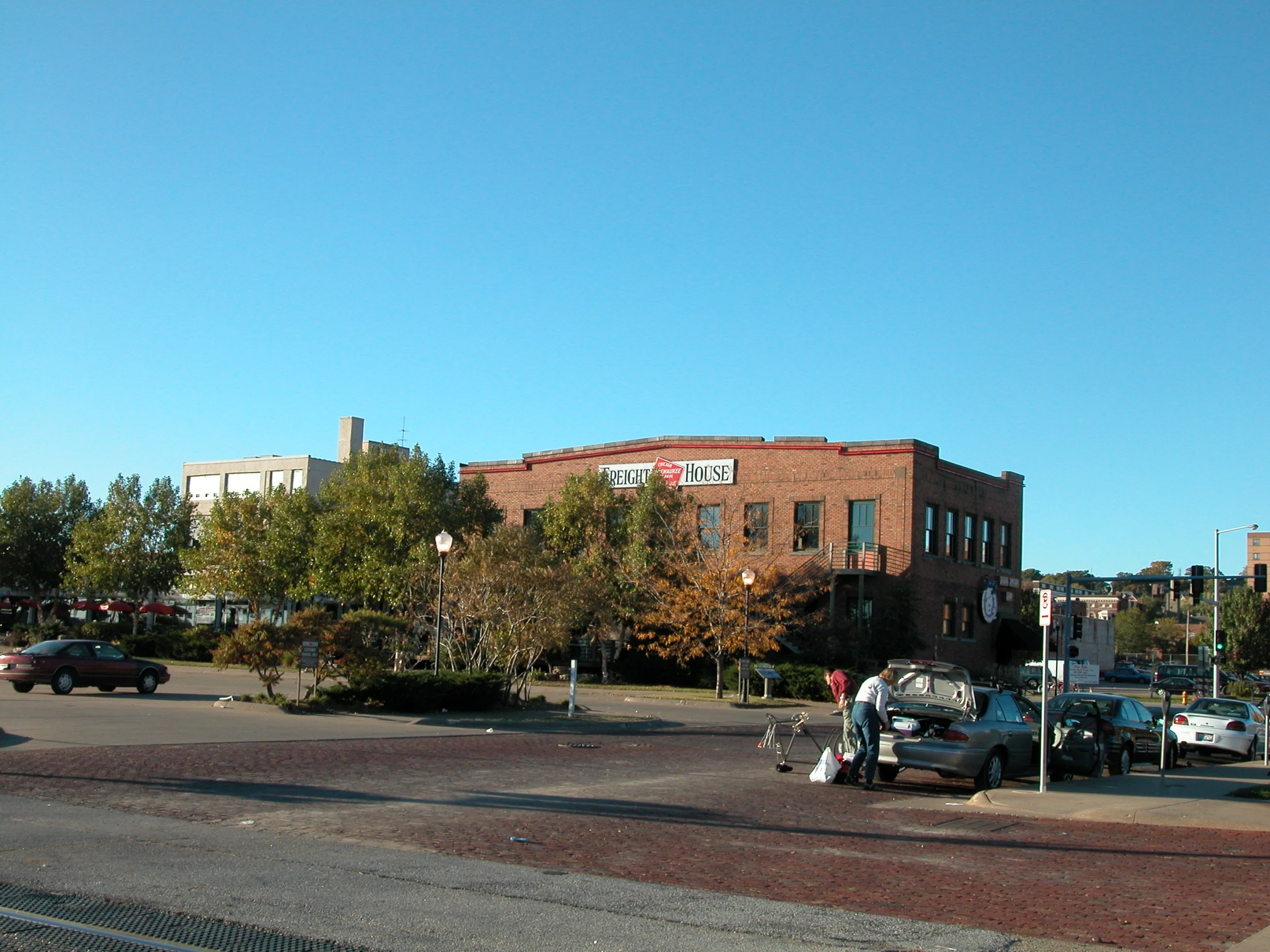 people and vehicles on street next to brick building