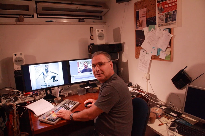 man at desk in office area with three monitors on wall